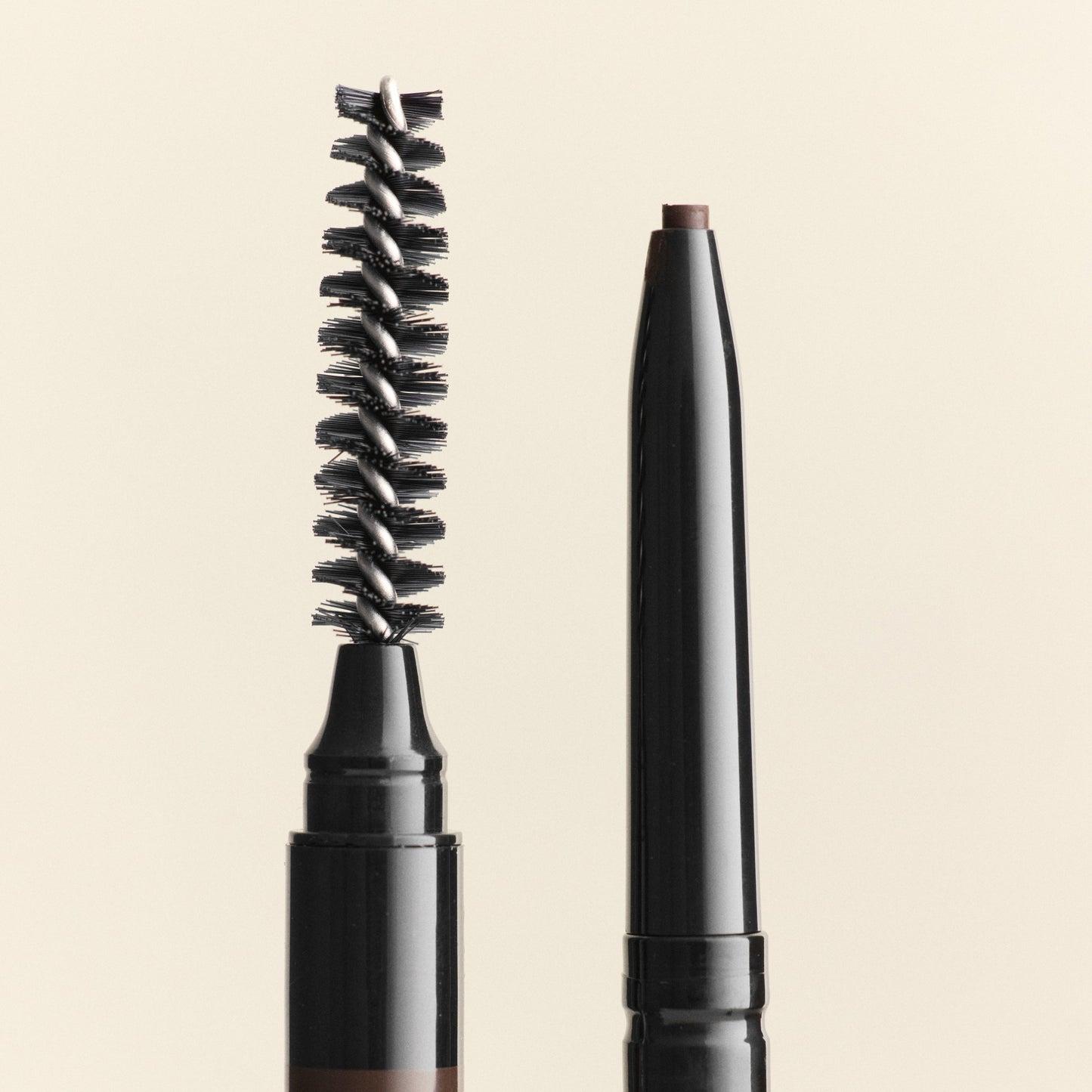 Eyebrow pencil with brush and cap on a beige background