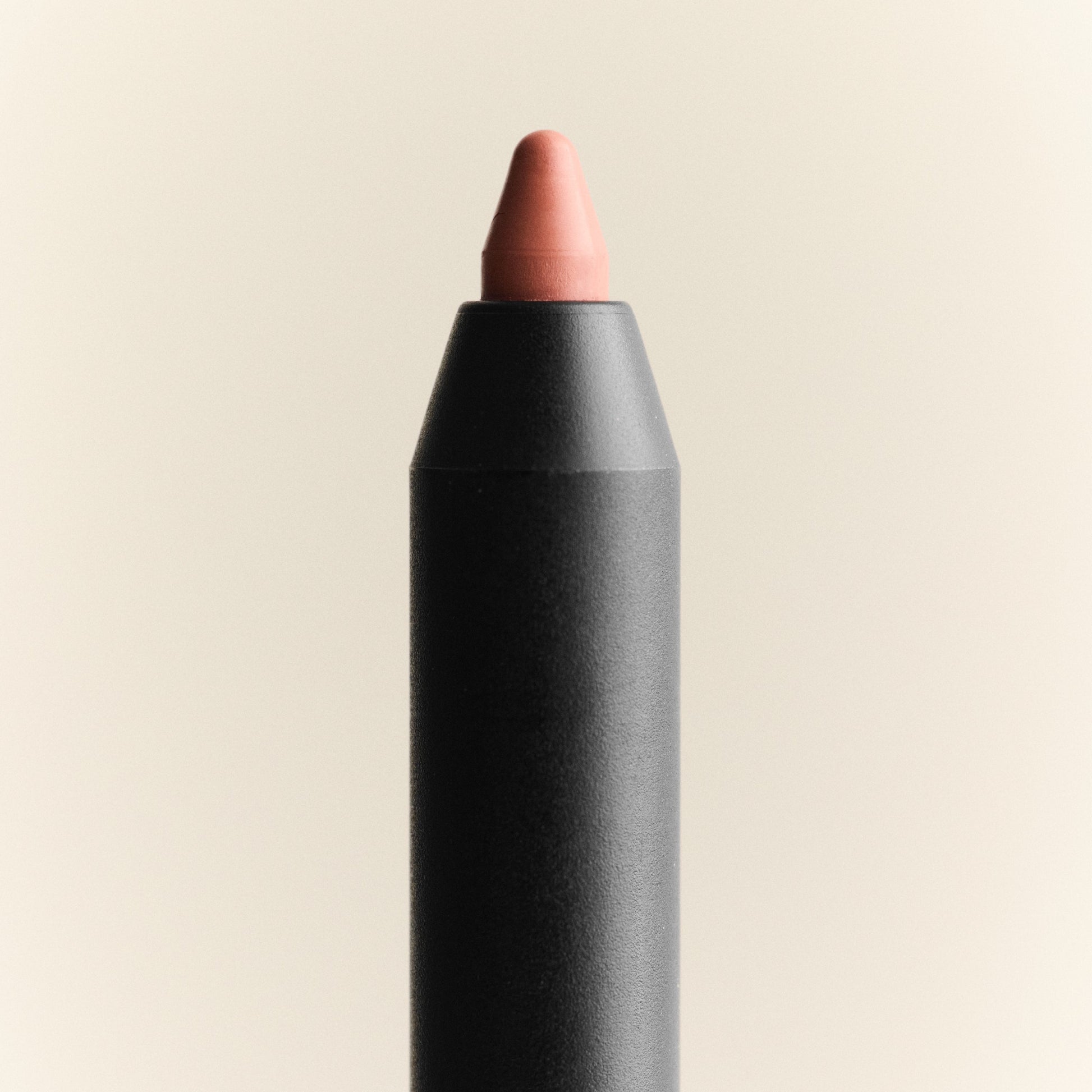 Lip crayon with a black casing and pink tip on a beige background