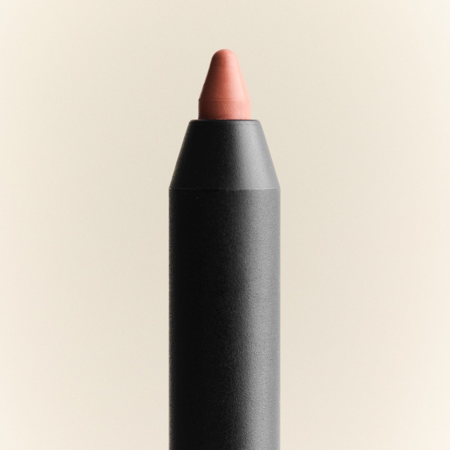 Lip crayon with a black casing and pink tip on a beige background